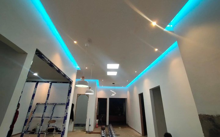 Plafon bertingkat dengan lampu LED di ruangan yang sedang dikerjakan