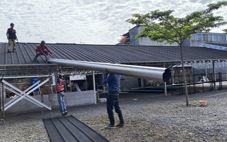 Tukang mengangkat lembaran atap pada pekerjaan renovasi