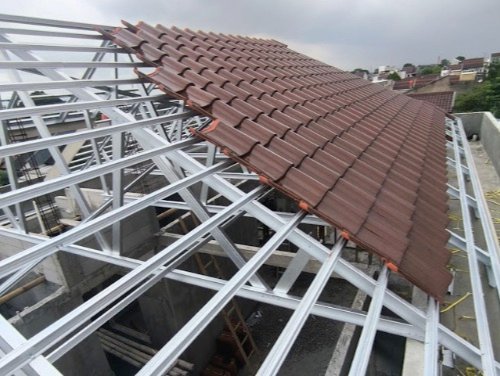 Rangka atap baja ringan yang sedang ditutup genteng metal