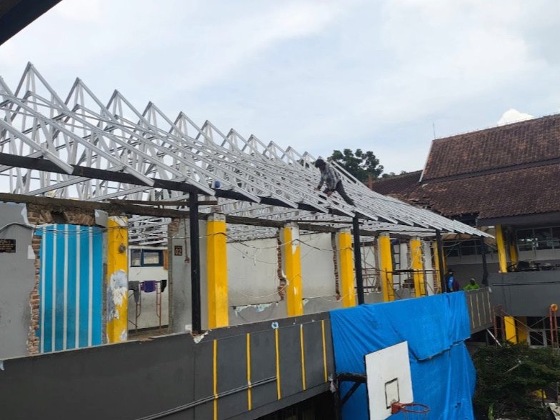 Pekerja memasang kuda kuda baja ringan di atas ruang kelas SDN Kopo